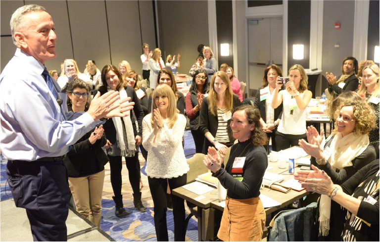 Rob Salafia leading a room of leaders on their feet